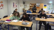 Schülerinnen und Schüler einer Willkommensklasse aus Düsseldorf sitzen im Klassenraum
